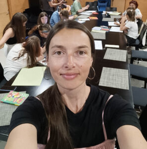 Olgan ottama selfie. Taustalla näkyy ukrainalaisia lapsia pöydän ääressä.