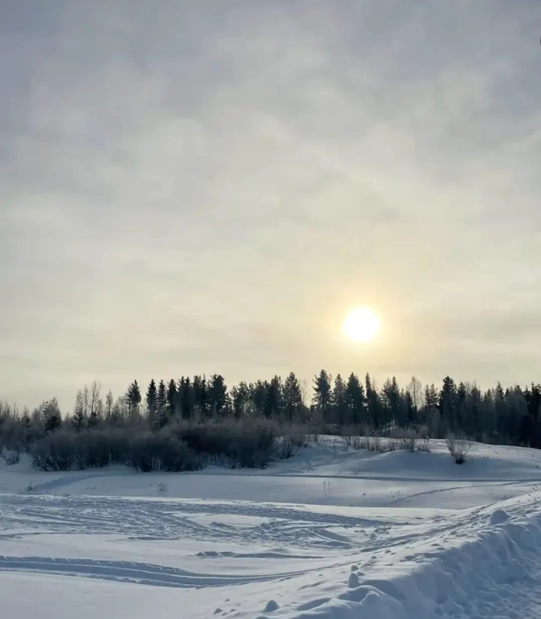 Kevät aurinko paistaa lumisessa maisemassa.