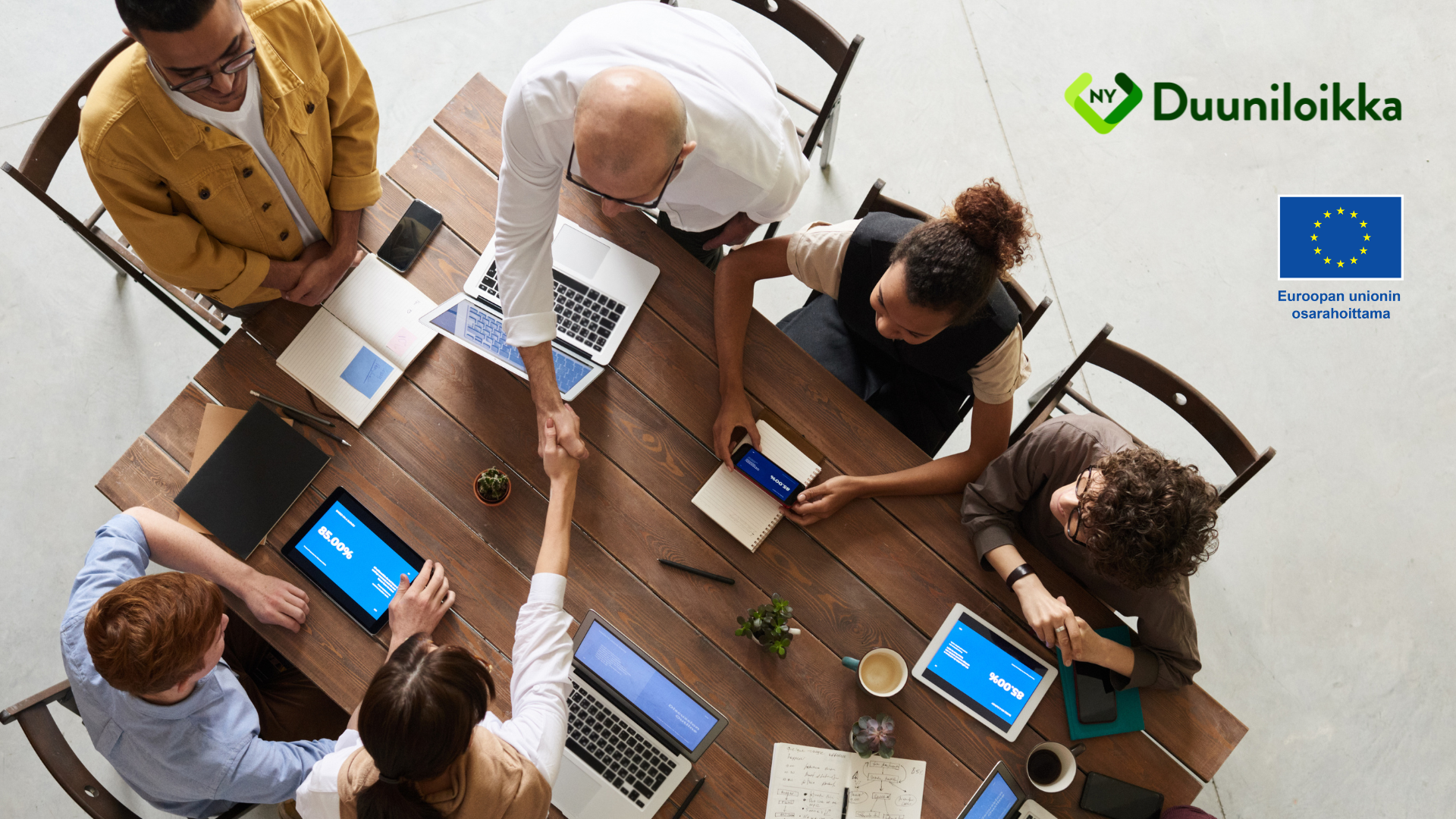 Ihmisiä pöydän ääressä yläpuolelta kuvattuna. Euroopan unionin osarahoittama.